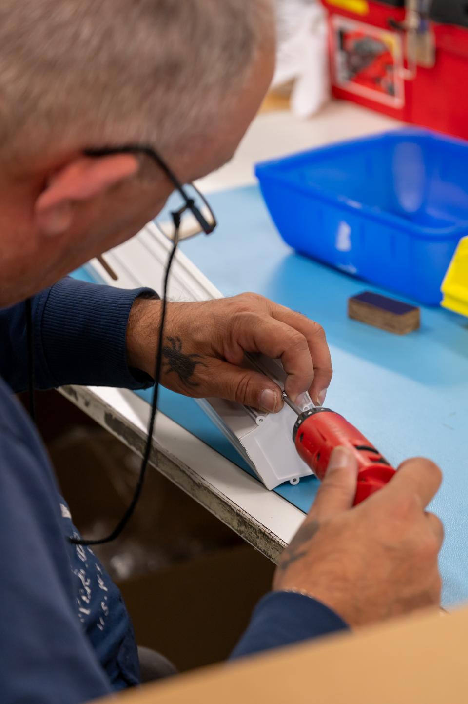 Een productiemedewerker schroeft een kap op een armatuur
