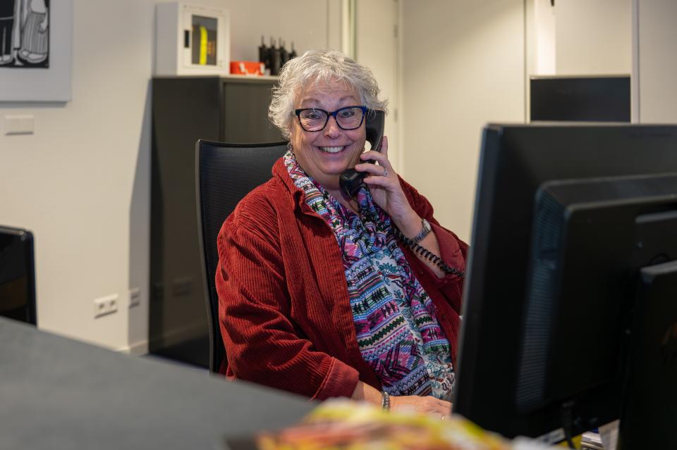 Receptiemedewerker zit achter de balie te telefoneren