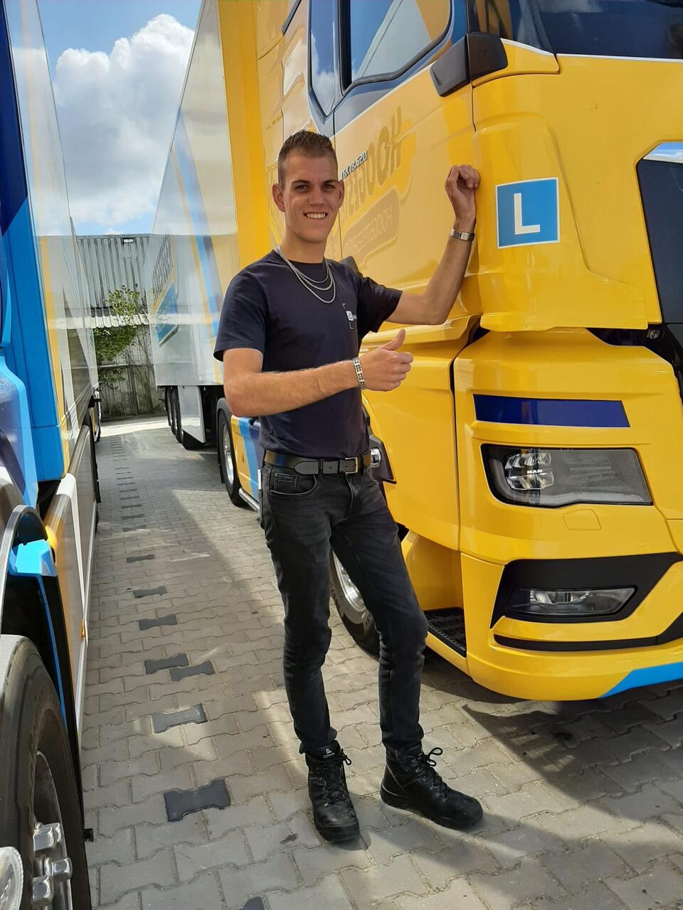 Matthias staat met zijn duim omhoog voor een lesvrachtwagen